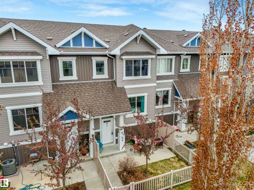 Contemporary townhome exterior featuring multi-toned siding, gabled rooflines, multiple windows, a white entry door, and a private enclosed patio area - 44 1140 Chappelle Boulevard, Edmonton, AB - Outdoor With Facade