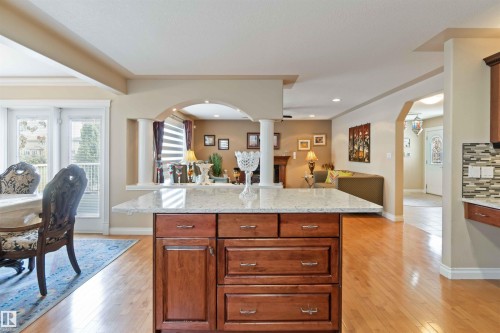 Kitchen island featuring a light-colored countertop and wood-finish cabinetry, set on wood-finish flooring - 6116 53 Avenue, Beaumont, AB - Indoor