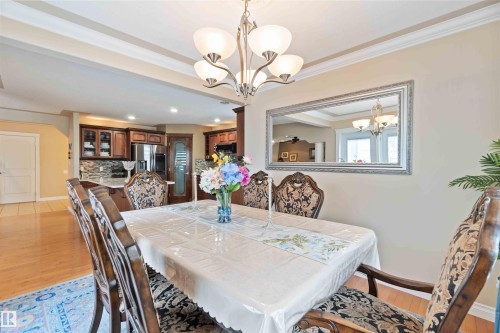 Dining area featuring a tray ceiling, chandelier lighting, and wood-finish flooring - 6116 53 Avenue, Beaumont, AB - Indoor Photo Showing Dining Room