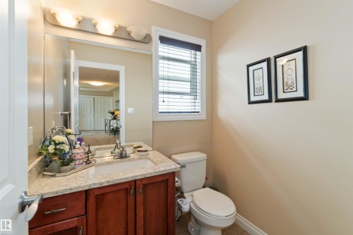 Powder room featuring a wood vanity with a light-colored countertop, an undermount sink, and a multi-bulb vanity light fixture - 6116 53 Avenue, Beaumont, AB - Indoor Photo Showing Bathroom