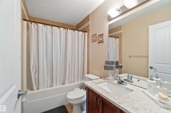 Bathroom featuring a shower-tub combination, a vanity with a light-colored countertop, and a large wall-mounted mirror - 