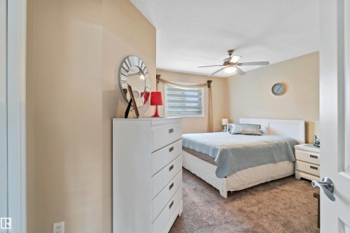 Carpeted bedroom with a window featuring blinds, a ceiling fan with integrated lighting, and neutral wall tones - 6116 53 Avenue, Beaumont, AB - Indoor Photo Showing Bedroom