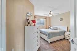 Carpeted bedroom with a window featuring blinds, a ceiling fan with integrated lighting, and neutral wall tones - 