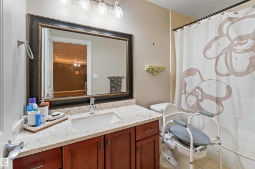 Bathroom featuring a wood-finish vanity with a light-colored countertop and an undermount sink - 6116 53 Avenue, Beaumont, AB - Indoor Photo Showing Bathroom