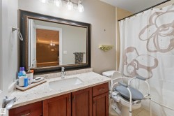 Bathroom featuring a wood-finish vanity with a light-colored countertop and an undermount sink - 