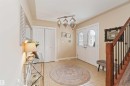 Entryway featuring double doors with decorative glass panels, tile flooring, a built-in closet, a wooden staircase with black iron balusters, and a unique multi-light fixture - 6116 53 Avenue, Beaumont, AB  - Indoor Photo Showing Other Room 