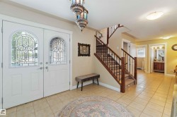 Entryway featuring double doors with decorative glass panels, a tiled floor, and a staircase with wood newel posts and metal balusters - 