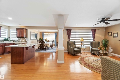 Hardwood flooring throughout featuring a kitchen island with stone countertop, wood cabinetry, and a tile backsplash - 6116 53 Avenue, Beaumont, AB - Indoor