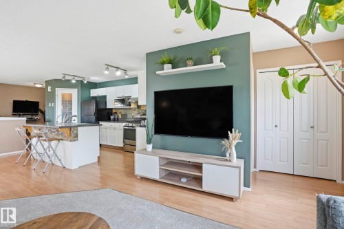 Open-concept living area featuring light wood-finish flooring, a contemporary entertainment center, and a media wall with shelving - 14017 156 Avenue, Edmonton, AB - Indoor