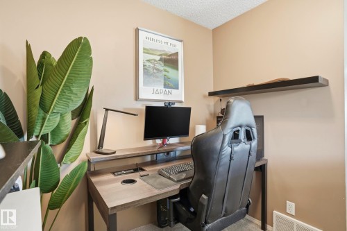 Dedicated workspace featuring a wood-finish desk, wall-mounted shelving, and warm neutral wall tones - 14017 156 Avenue, Edmonton, AB - Indoor Photo Showing Office