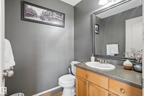 Vanity with wood-finish cabinetry, solid surface countertop, and an undermount oval sink - 14017 156 Avenue, Edmonton, AB - Indoor Photo Showing Bathroom