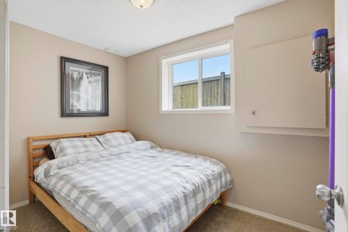 Neutral-toned room featuring a window with exterior views, light-colored walls, and textured carpeting - 14017 156 Avenue, Edmonton, AB - Indoor Photo Showing Bedroom