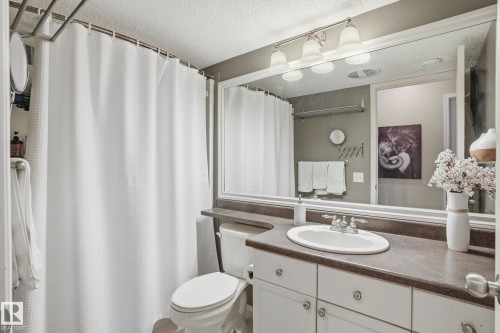 Bathroom featuring a white vanity with an integrated sink, a dark countertop, and a large framed mirror with overhead lighting - 14017 156 Avenue, Edmonton, AB - Indoor Photo Showing Bathroom