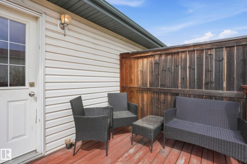 Outdoor patio featuring wood-finish decking, privacy fencing, and white vinyl siding - 14017 156 Avenue, Edmonton, AB - Outdoor With Deck Patio Veranda With Exterior
