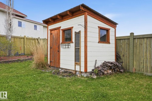 Exterior storage shed with a wood door and trim, two windows, and white siding - 14017 156 Avenue, Edmonton, AB - Outdoor