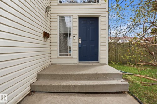 Entryway featuring a dark blue paneled door, white siding exterior, an exterior wall sconce, and a concrete stoop with steps - 14017 156 Avenue, Edmonton, AB - Outdoor With Exterior