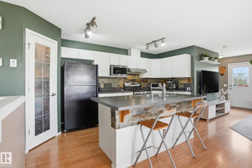 Open-concept kitchen featuring white cabinetry, a stone tile backsplash, and track lighting - 14017 156 Avenue, Edmonton, AB - Indoor Photo Showing Kitchen