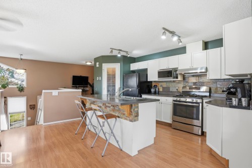 Kitchen with wood-finish flooring, white cabinetry, and stainless steel appliances - 14017 156 Avenue, Edmonton, AB - Indoor Photo Showing Kitchen With Double Sink