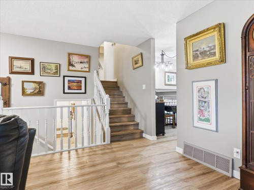 Split-level interior featuring wood-finish flooring, a staircase with white balusters, and light gray wall paint - 18627 62A Avenue, Edmonton, AB - Indoor Photo Showing Other Room