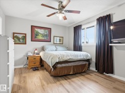Bedroom featuring wood-finish flooring, a ceiling fan with integrated lighting, a window with dark drapery, and neutral wall paint - 