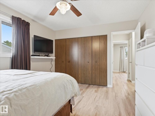 Bedroom featuring wood-finish flooring, a ceiling fan with integrated lighting, and bi-fold closet doors - 18627 62A Avenue, Edmonton, AB - Indoor Photo Showing Bedroom