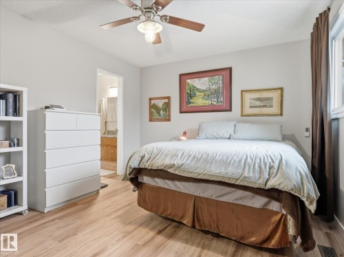 Spacious room featuring wood-finish flooring, a ceiling fan, and a window with brown drapery - 18627 62A Avenue, Edmonton, AB - Indoor Photo Showing Bedroom