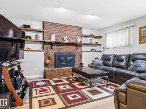 Brick fireplace with an integrated firebox, flanked by built-in shelving and light wood-finish flooring - 18627 62A Avenue, Edmonton, AB - Indoor Photo Showing Living Room With Fireplace