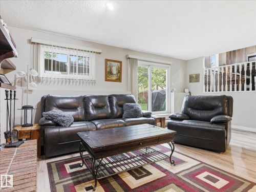 Inviting living space featuring wood-finish flooring, a brick-clad fireplace, and sliding glass door access to the exterior - 18627 62A Avenue, Edmonton, AB - Indoor Photo Showing Living Room