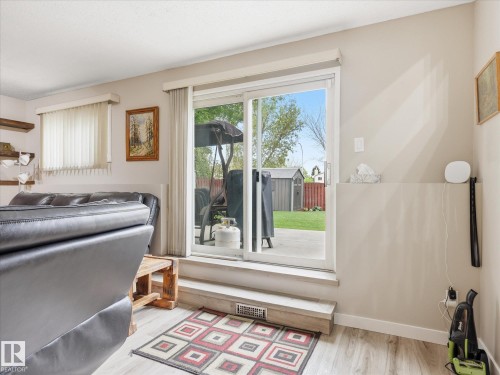 Sliding glass door opening to an outdoor patio with a manicured lawn and garden shed - 18627 62A Avenue, Edmonton, AB - Indoor