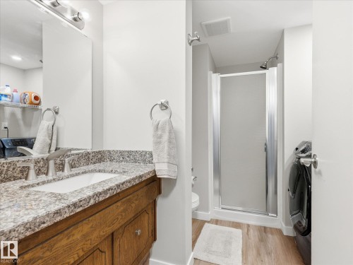 Bathroom vanity featuring a granite countertop with an undermount sink and a wood-finish cabinet - 18627 62A Avenue, Edmonton, AB - Indoor Photo Showing Bathroom