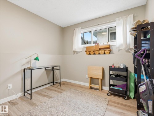 Room featuring wood-finish flooring, neutral wall tones, and a window with white curtains - 18627 62A Avenue, Edmonton, AB - Indoor Photo Showing Other Room
