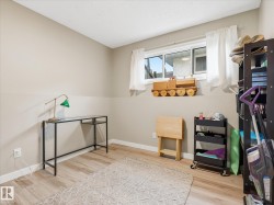 Room featuring wood-finish flooring, neutral wall tones, and a window with white curtains - 