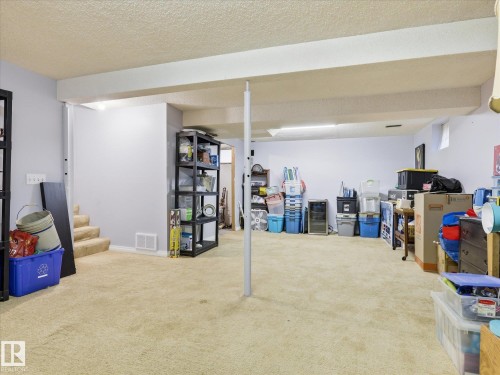 Carpeted lower level featuring a drop ceiling, painted walls, and structural support beams - 18627 62A Avenue, Edmonton, AB - Indoor