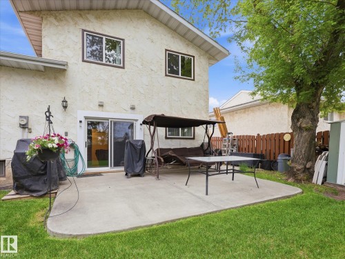 Rear exterior featuring a concrete patio, sliding glass door access, stucco siding, and a wooden fence - 18627 62A Avenue, Edmonton, AB - Outdoor With Deck Patio Veranda With Exterior