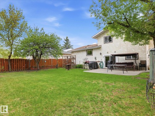 Expansive backyard featuring a manicured lawn, established trees, and a wooden privacy fence - 18627 62A Avenue, Edmonton, AB - Outdoor With Deck Patio Veranda With Backyard