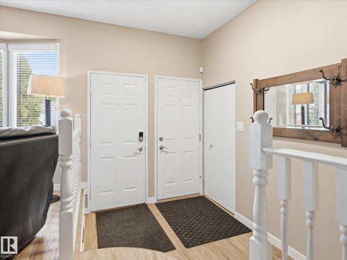 Entryway featuring wood-finish flooring, white paneled doors, and a staircase with white balusters - 18627 62A Avenue, Edmonton, AB - Indoor Photo Showing Other Room