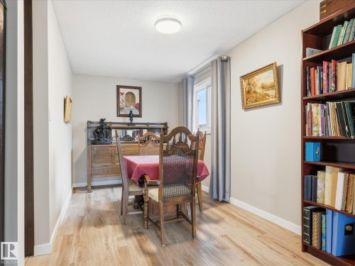 Neutral wall paint, wood-finish flooring, and a bright ceiling light fixture - 18627 62A Avenue, Edmonton, AB - Indoor Photo Showing Dining Room