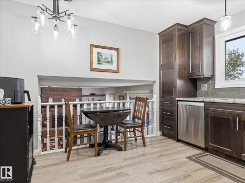 Kitchen featuring wood-finish flooring, dark wood cabinetry, light-toned countertops, and a subway tile backsplash - 18627 62A Avenue, Edmonton, AB - Indoor