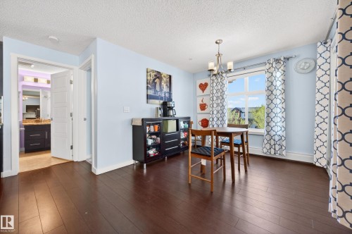 Spacious area featuring dark wood-finish flooring and light blue walls - 340 6076 Schonsee Way, Edmonton, AB - Indoor