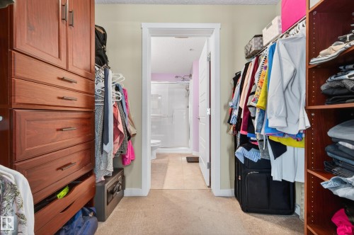 Walk-in closet with built-in wood cabinetry, shelving, and hanging rods - 340 6076 Schonsee Way, Edmonton, AB - Indoor With Storage