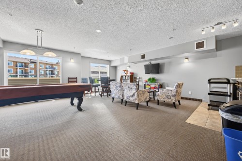 Spacious common area featuring a billiard table, extensive carpeting, large windows, and track lighting - 340 6076 Schonsee Way, Edmonton, AB - Indoor