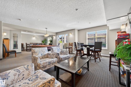 Spacious recreation area featuring a billiards table, multiple seating arrangements, and broad windows - 340 6076 Schonsee Way, Edmonton, AB - Indoor Photo Showing Living Room