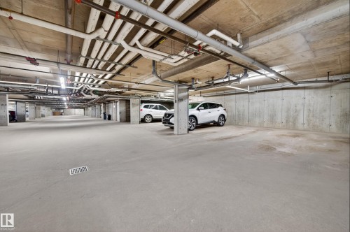 Underground parking garage featuring concrete flooring and exposed concrete ceiling with utility piping - 340 6076 Schonsee Way, Edmonton, AB - Indoor Photo Showing Garage