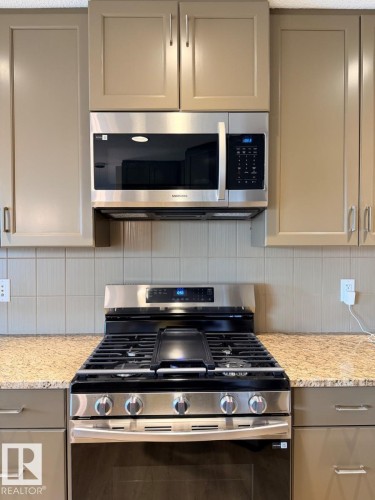 Stainless steel range with a built-in griddle, complemented by an over-the-range microwave - 648 178 Street, Edmonton, AB - Indoor Photo Showing Kitchen With Upgraded Kitchen
