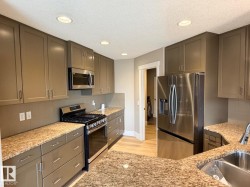 Kitchen featuring recessed lighting, extensive cabinetry, stone-finish countertops, stainless steel appliances, and wood-finish flooring - 