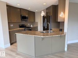 Kitchen featuring a U-shaped island with a double basin sink, granite-style countertops, and full-height cabinetry - 