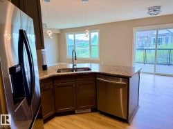 Kitchen featuring wood-finish flooring, dark wood cabinetry, a double basin sink with a high-arc faucet, and granite-style countertops - 