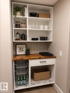 Built-in white cabinetry with open shelving, butcher block countertop, and integrated pull-out wire baskets - 