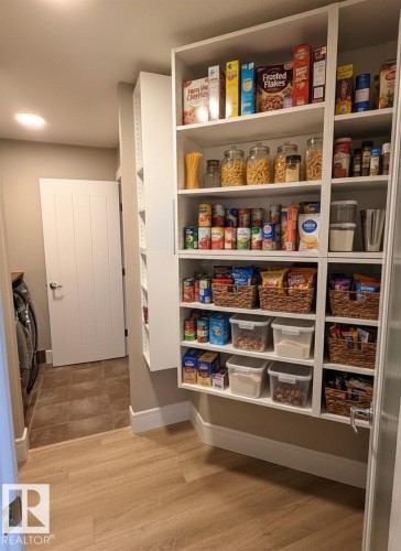 Spacious pantry featuring extensive built-in shelving, light wood-finish flooring, and white baseboards - 648 178 Street, Edmonton, AB - Indoor