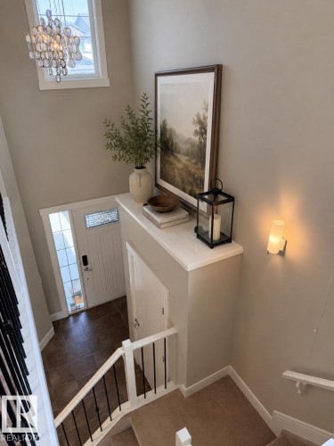 Foyer with tiled flooring, white front door featuring decorative glass, and a stylish glass chandelier - 648 178 Street, Edmonton, AB - Indoor Photo Showing Other Room